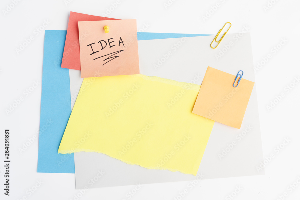 Idea text written on sticky note with pushpin and paperclip on white board Idea text written on sticky note with pushpin and paperclip on white board