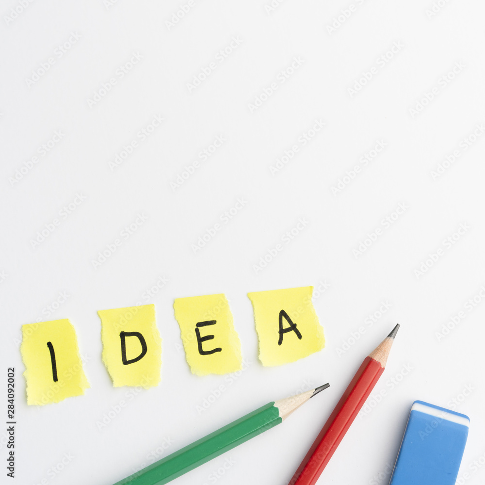 Idea text on torn yellow pieces paper with pencils and eraser over white background Idea text on torn yellow pieces paper with pencils and eraser over white background