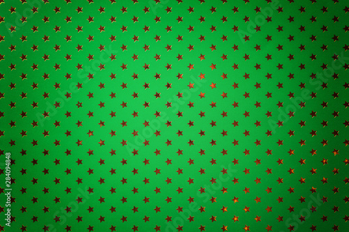Dark green background from metal foil paper with a golden stars pattern.