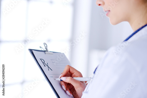 Portrait of a young female doctor. The doctor writes down the diagnosis. The doctor writes a prescription in the hospital to the patient