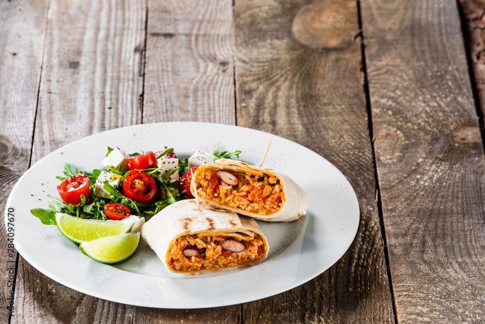 Burrito with vegetable salad on white plate Burrito with vegetable salad on white plate