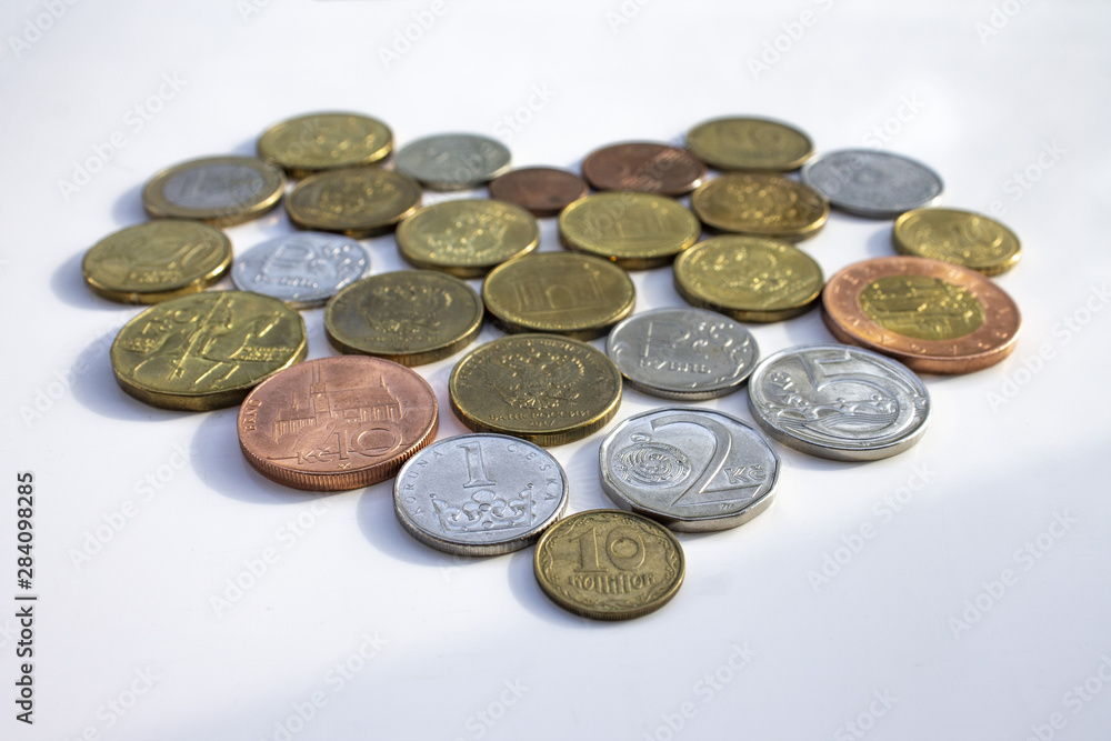 Coins of different countries laid out in the shape of a heart on a white background. Coins of different countries laid out in the shape of a heart on a white background.