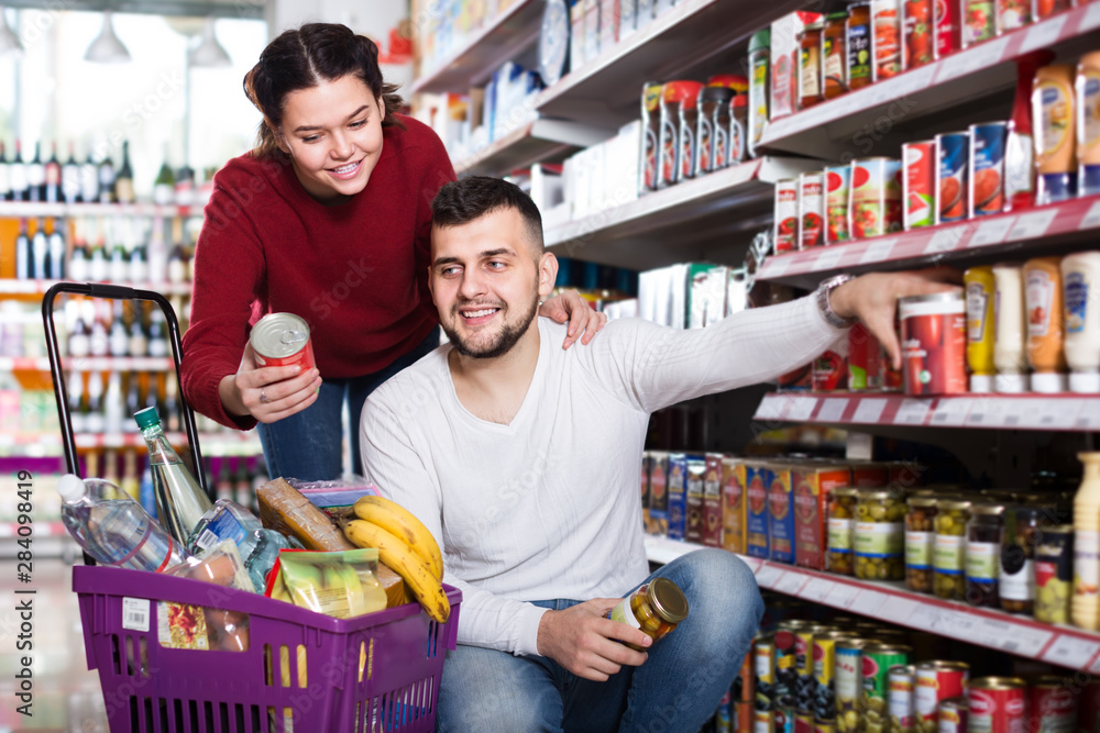 satisfied couple choosing purchasing canned food for week at supermarket
