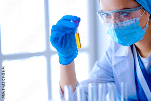 Woman holding test tube. Chemist is analyzing sample in laboratory room