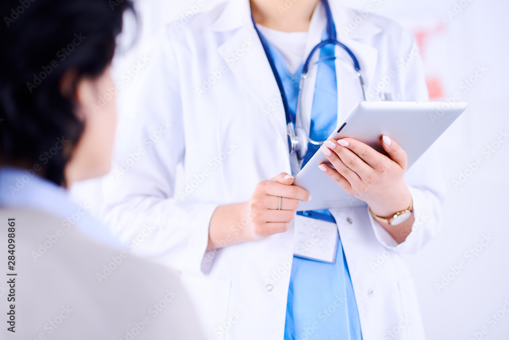 Doctor talking to a patient in a hospital and holding a tablet. Doctor talking to a patient in a hospital and holding a tablet.
