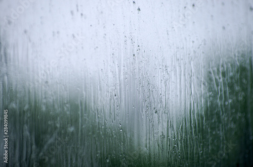 Rain drops on window glasses surface with bokeh background.