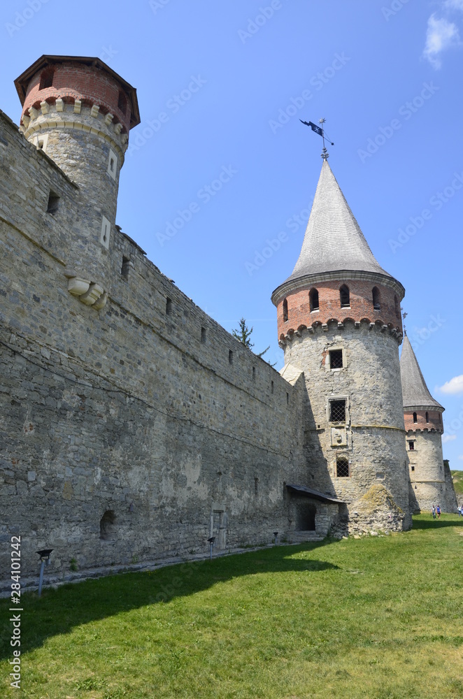 The wall and towers of the magic fortress in Kamyanets-Podilsky in Ukraine against the background of a blue-haired sky