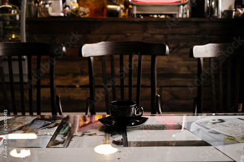  black cup of coffee on a table in a cafe interior on a dark background photo