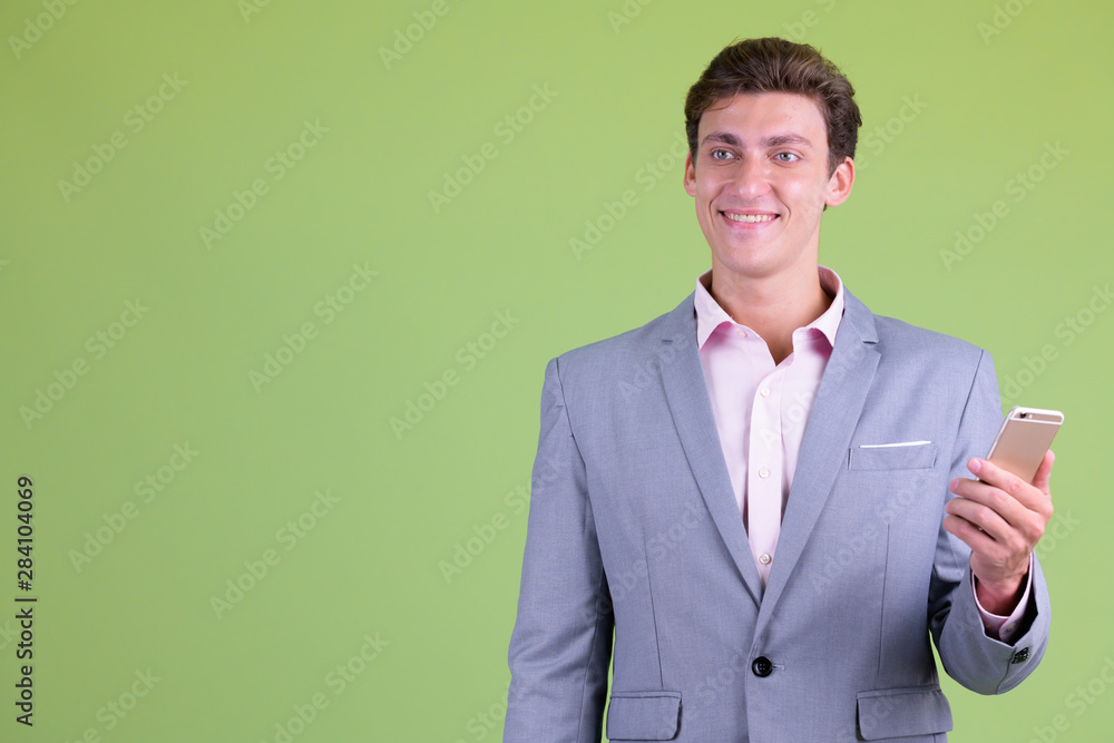 Happy young handsome businessman thinking while using phone Happy young handsome businessman thinking while using phone