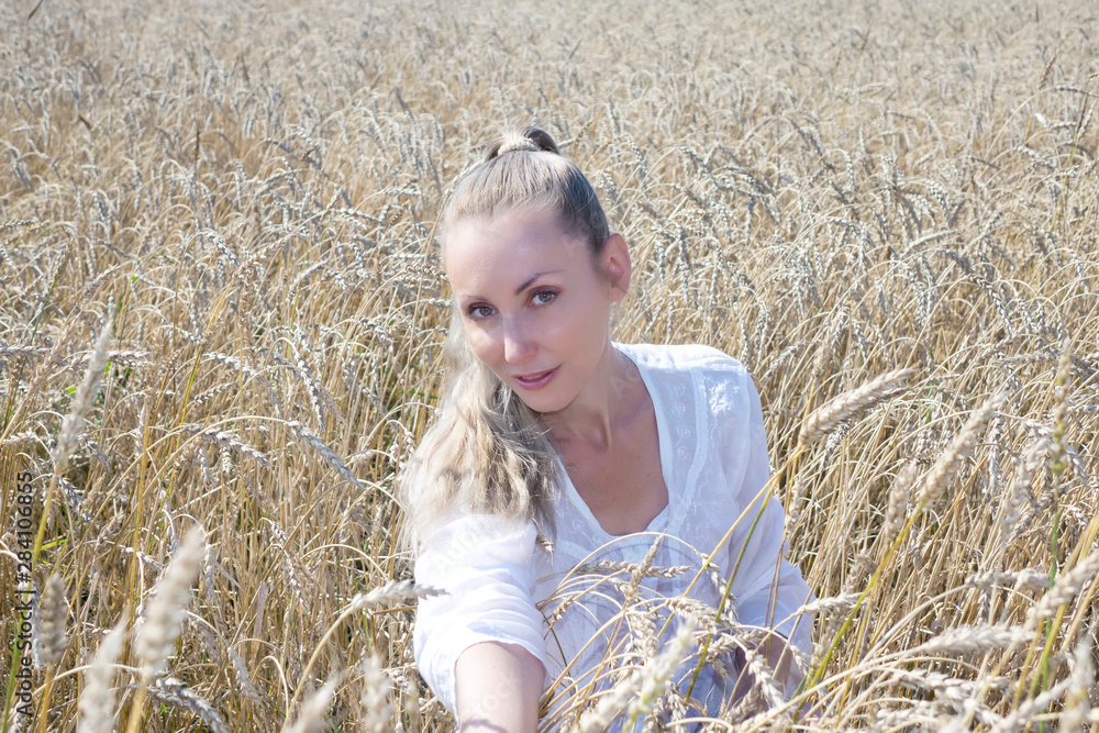 portrait of a beautiful young woman in a white blouse with long blond hair in a field of golden wheat ears on a summer day portrait of a beautiful young woman in a white blouse with long blond hair in a field of golden wheat ears on a summer day