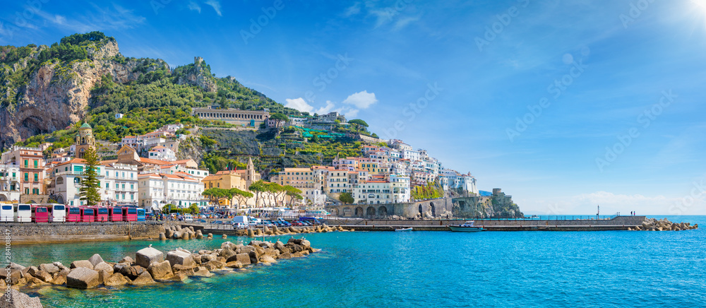 Panorama of Amalfi on hills leading down to coast, comfortable beaches and azure sea on Amalfi Coast in Campania, Italy