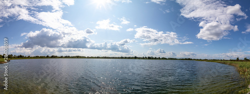Fototapeta Naklejka Na Ścianę i Meble -  Panoramic Banner with panorama of sunny clear Lake Clouds on the Sky reflected in Water