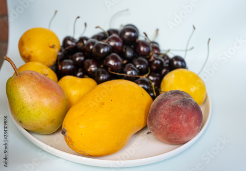 cherries  yellow plums  pear  mango and peach on white backround