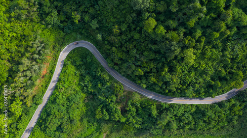 aerial above view green mountain forest in the rain season and curved road on the hill connecting countryside