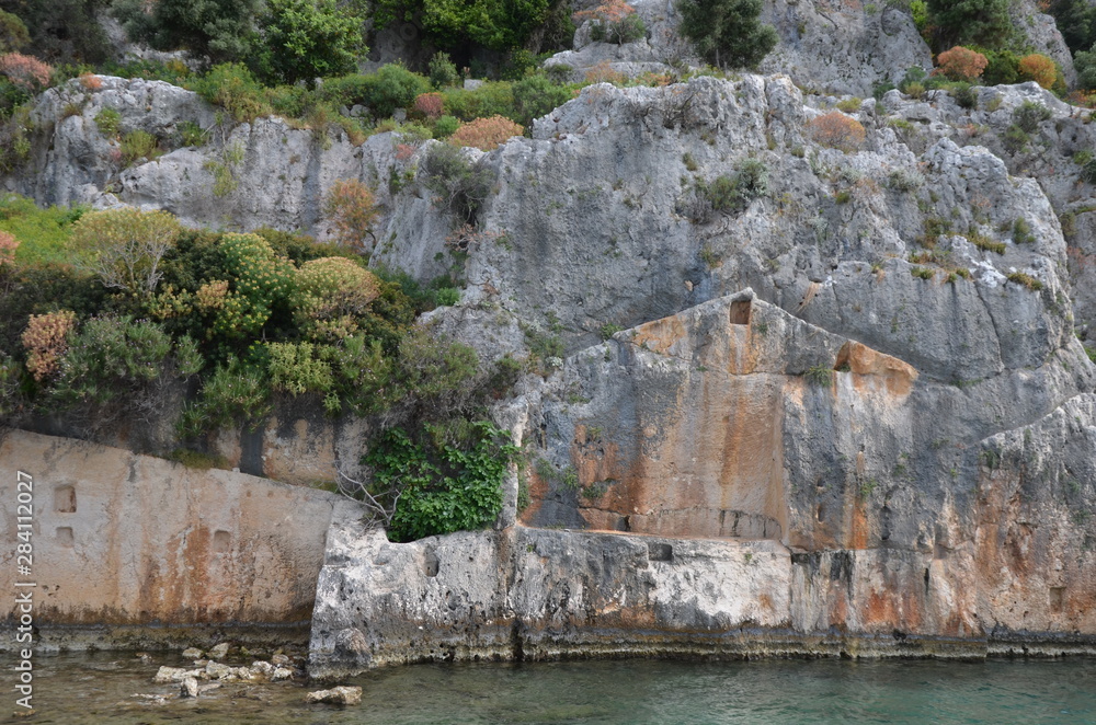 Kekova Island Sunken Ruins in Turkey. Rocks with ruined houses and trees and Mediterranean sea.