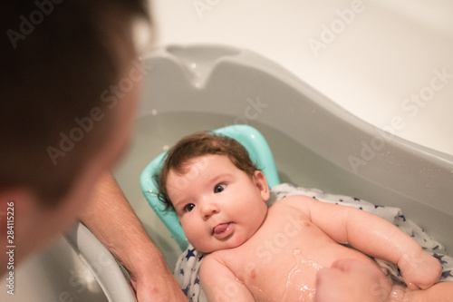 A father bathes his son. Hygiene and baby care. Portrait of a child being washed by his father. Soft tone. Bath time for a cute little newborn baby
