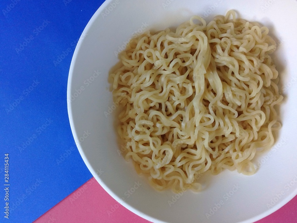 Ramen noodles in a white bowl with a colored background
