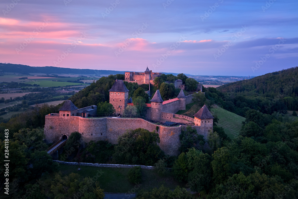 Helfstyn castle (German: Helfenstein, Helfstein), aerial view of a medieval gothic castle on a knoll over countryside. Castle walls in vibrant colors of setting sun. Czech landscape, Moravia region.