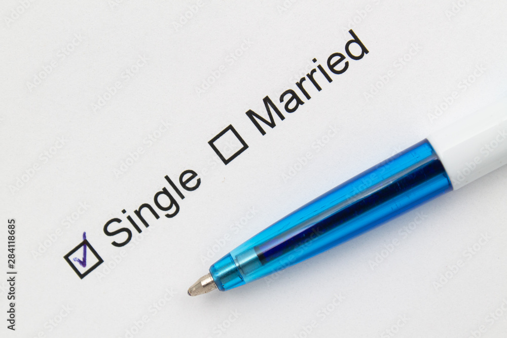 Single or married - checkmark on white paper with pen. Single or married - checkmark on white paper with pen.