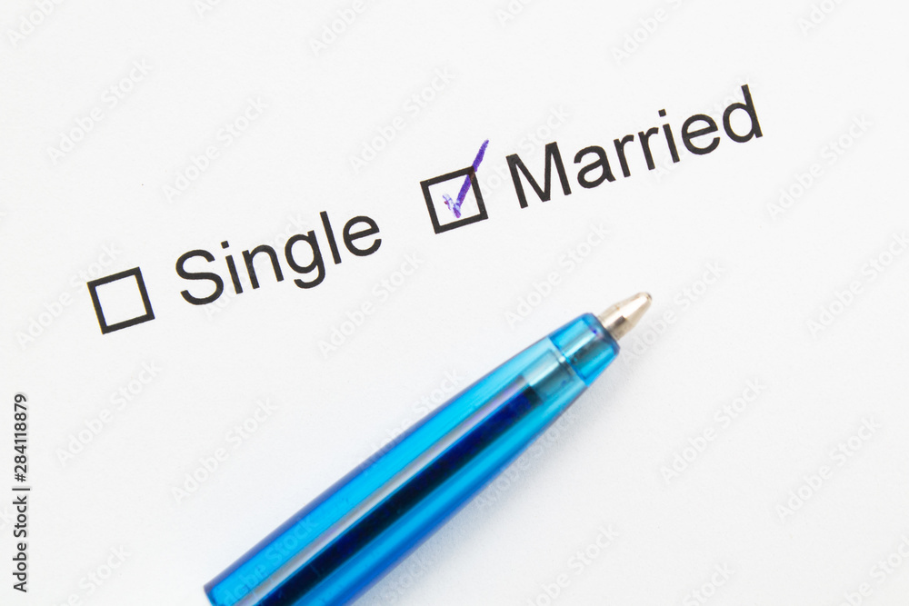 Single or married - checkmark on white paper with pen. Single or married - checkmark on white paper with pen.