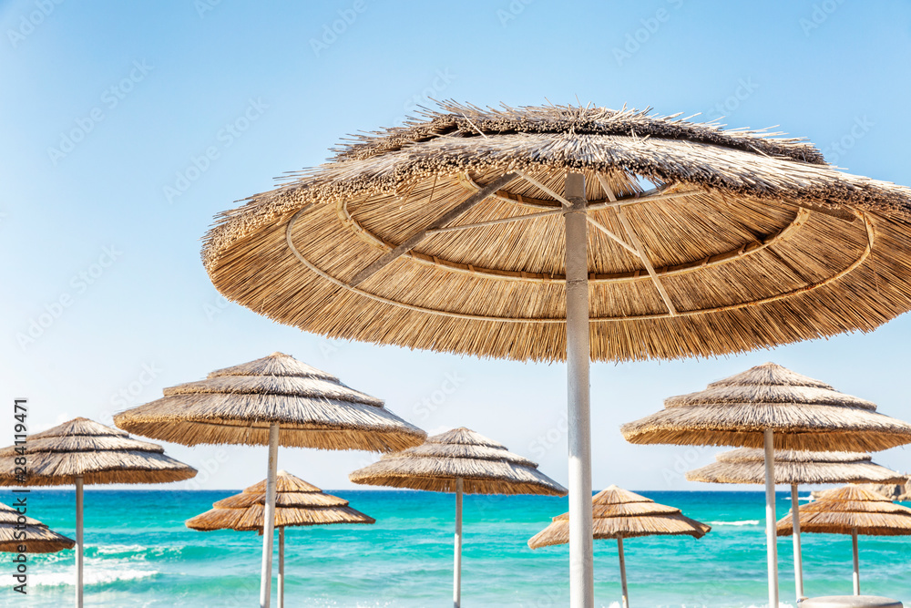 Thatched sun umbrellas on the beach against the background of the turquoise sea and clear blue sky. Thatched sun umbrellas on the beach against the background of the turquoise sea and clear blue sky.