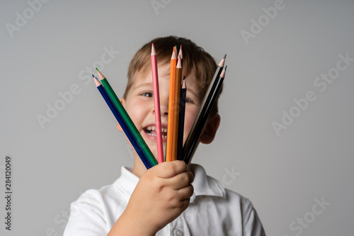 Closeup of child's hands with lots of colorful wax crayons pencils. Kid preparing stationary and student stuff. Back to school concept. photo