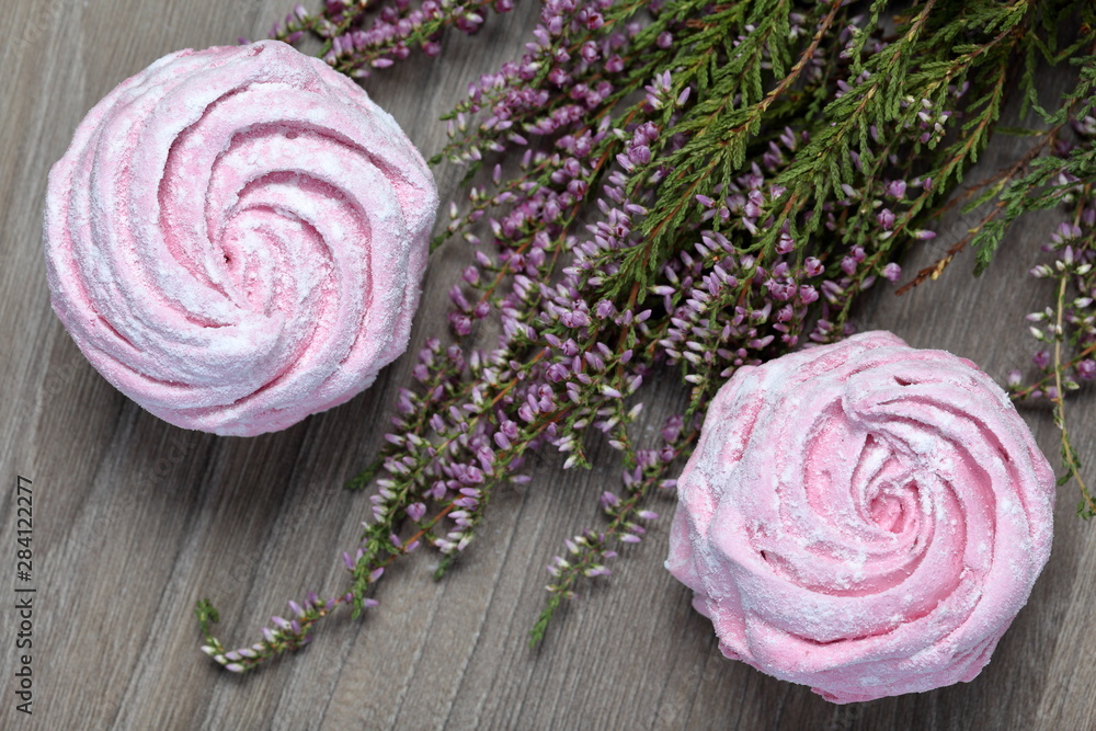 Pink marshmallows in icing sugar. Next to the decoration lies blooming heather. Pink marshmallows in icing sugar. Next to the decoration lies blooming heather.