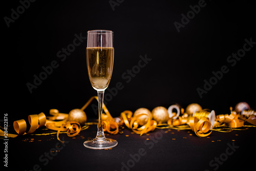 Gllasses of champagne on black stylish background with Place for text. Festive concept.Golden stylish decoration on black background. Sticky tape, Christmas balls, golden ribbon