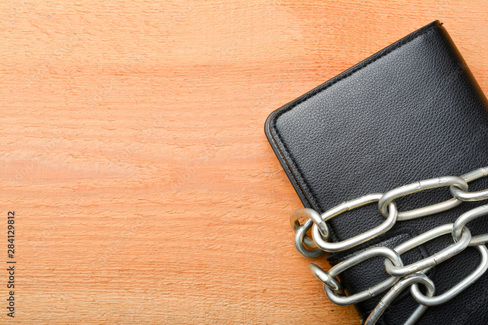 Wallet tied with a chain, a purse and a chain on a wooden background Wallet tied with a chain, a purse and a chain on a wooden background