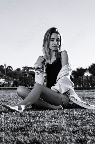 portrait of young blonde woman sitting oon the grass in photoshoot