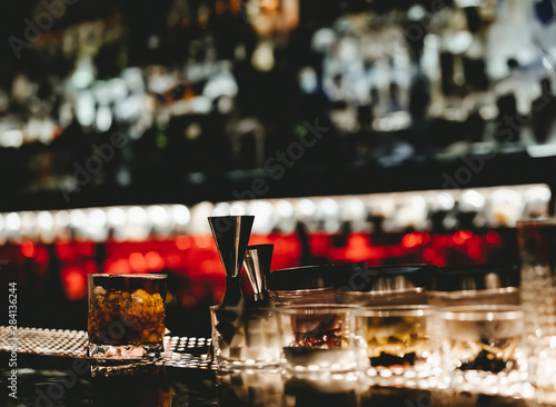 Night club pub scene with alcohol bottles and glass of whiskey and coke - Cocktail bar disco interior with dark lighting and background bokeh - Nightlife, lifestyle and social concept