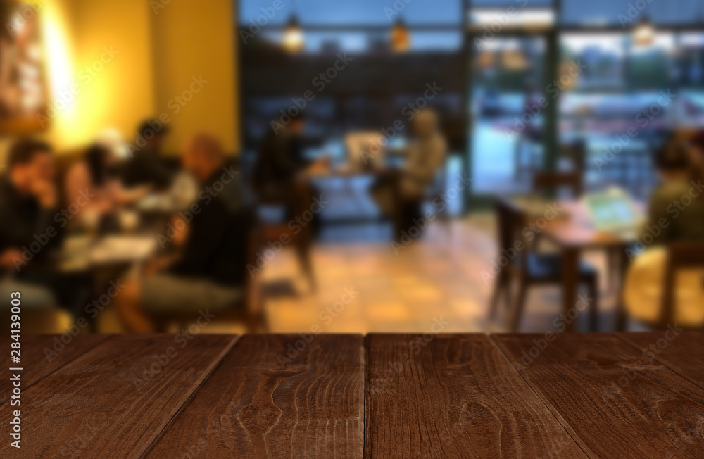 Wooden perspective table in front of abstract blurred background of cafe or restaurant 