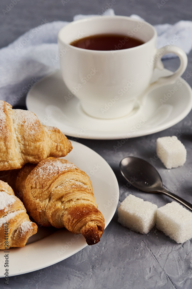 cup of tea, croissants, sugar cubes on a gray background, breakfast concept cup of tea, croissants, sugar cubes on a gray background, breakfast concept
