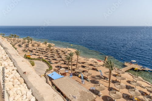 Sharm El Sheikh, Egypt - May, 2019: Beautiful beach with palm trees at sunset