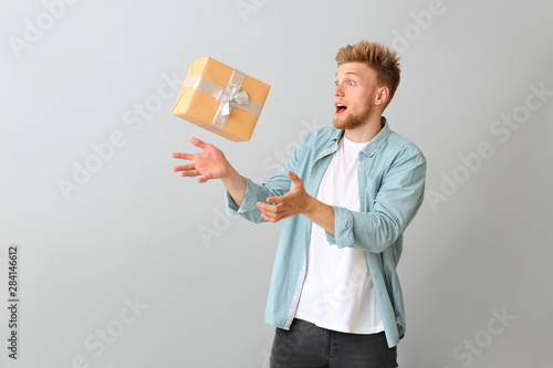 фотографія Young man catching gift box on light background