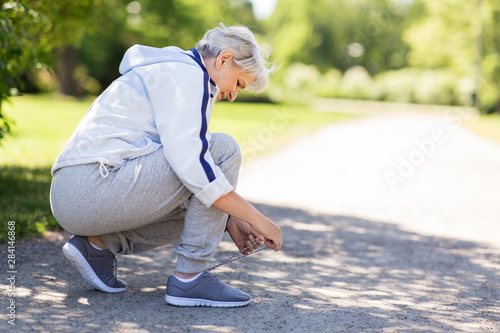 Bilde på lerret fitness, sport and healthy lifestyle concept - senior woman tying shoe laces at