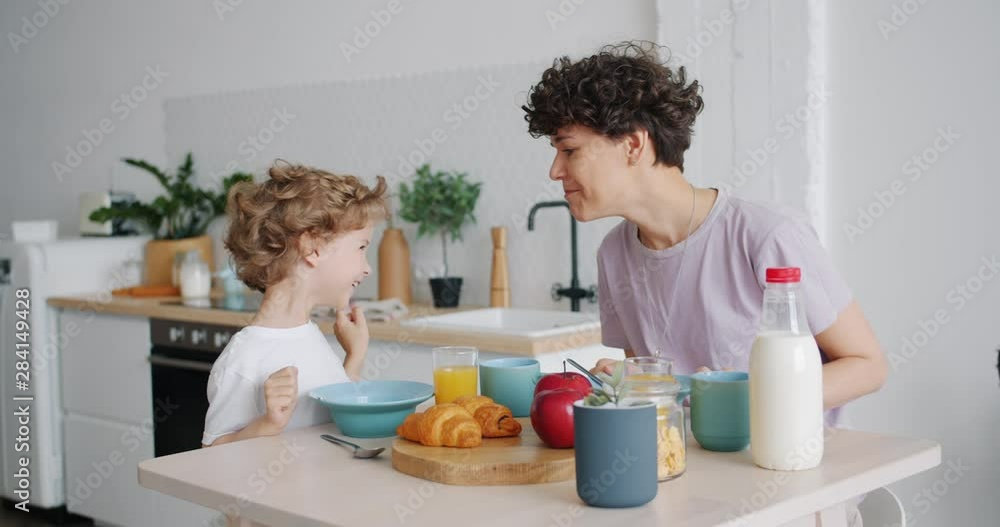 Slow motion of happy people mother and son having fun and enjoying breakfast cereal with milk in light kitchen in modern apartment. People and meals concept. Slow motion of happy people mother and son having fun and enjoying breakfast cereal with milk in light kitchen in modern apartment. People and meals concept.