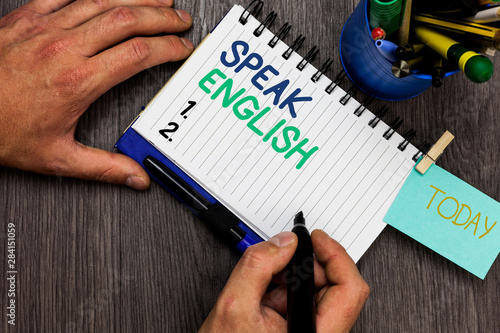 Conceptual hand writing showing Speak English. Business photo showcasing Study another Foreign Language Online Verbal Courses Man holding marker notebook reminder cup markers wood table photo