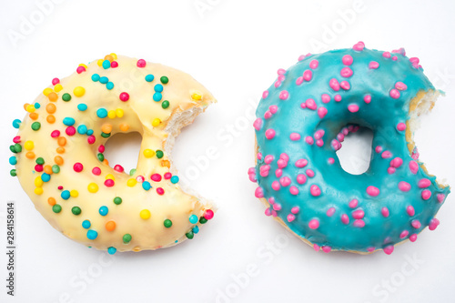 Blue and yellow donuts, two bitten donuts with bright sprinkles on a isolated background, food concept