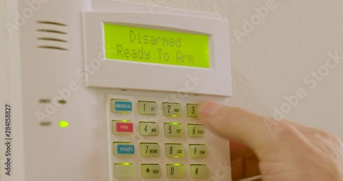 Closeup footage of a Caucasian male arming his home security system using a programmed designated code.
