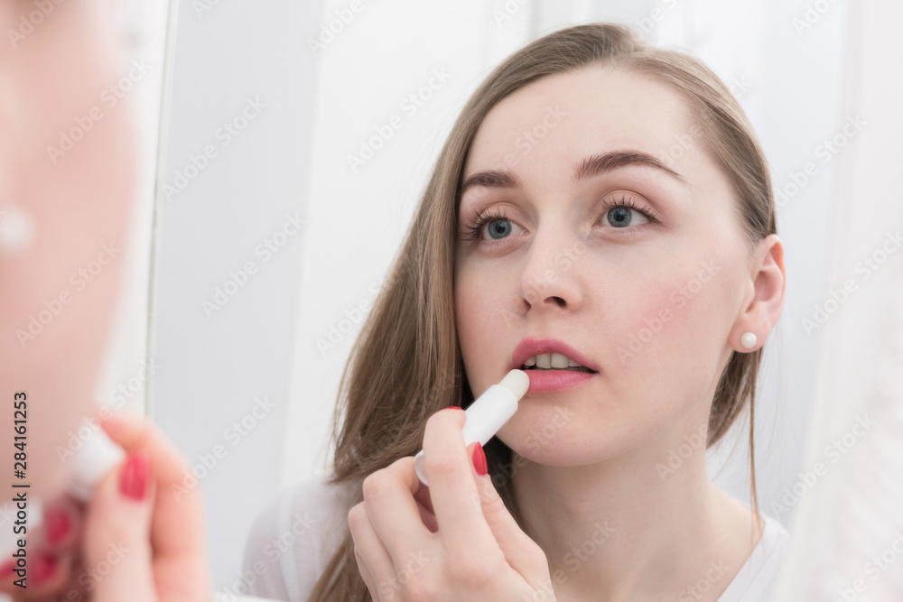 Attractive woman, looks in the mirror, using lipstick, morning routine, close up Attractive woman, looks in the mirror, using lipstick, morning routine, close up