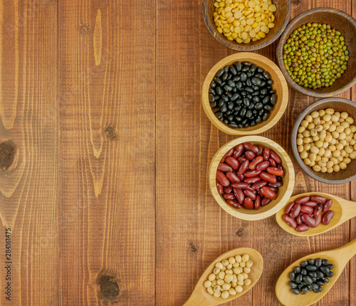 Flat lay,top view assorted beans including red bean,soybeans,black beans,mung beans on brown,beige wooden background with copy space 