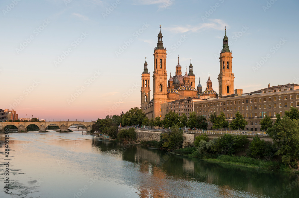 View of the cathedral of El Pilar de Zaragoza, next to the river Ebro, at sunset.