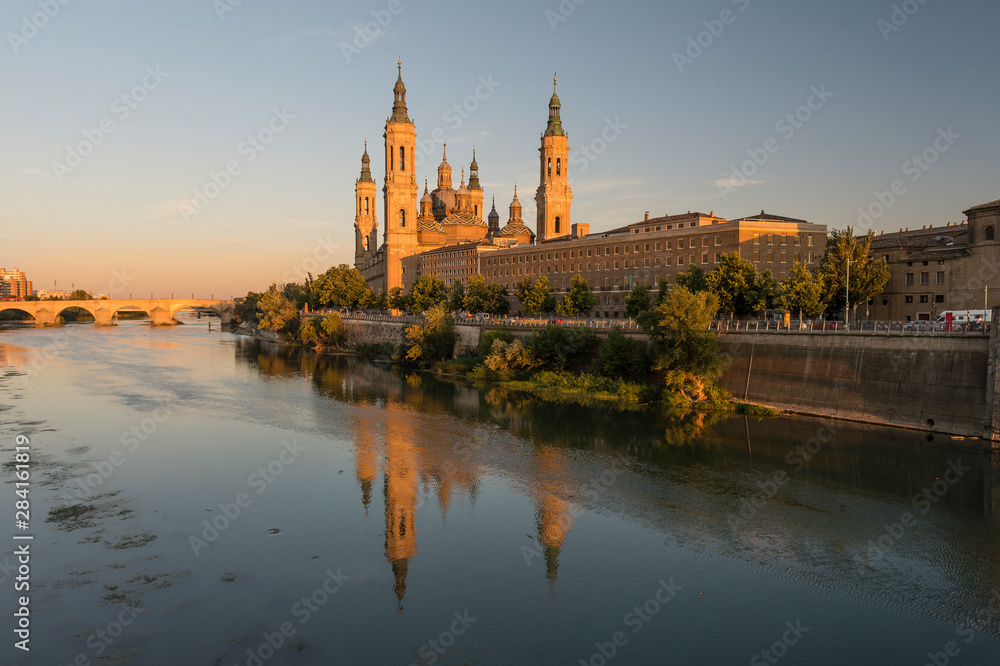 View of the cathedral of El Pilar de Zaragoza, next to the river Ebro, at sunset.