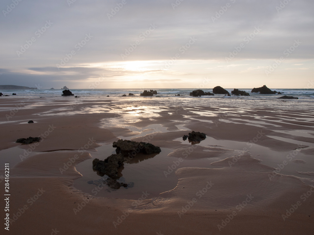 puesta de sol en playa con la marea baja y rocas