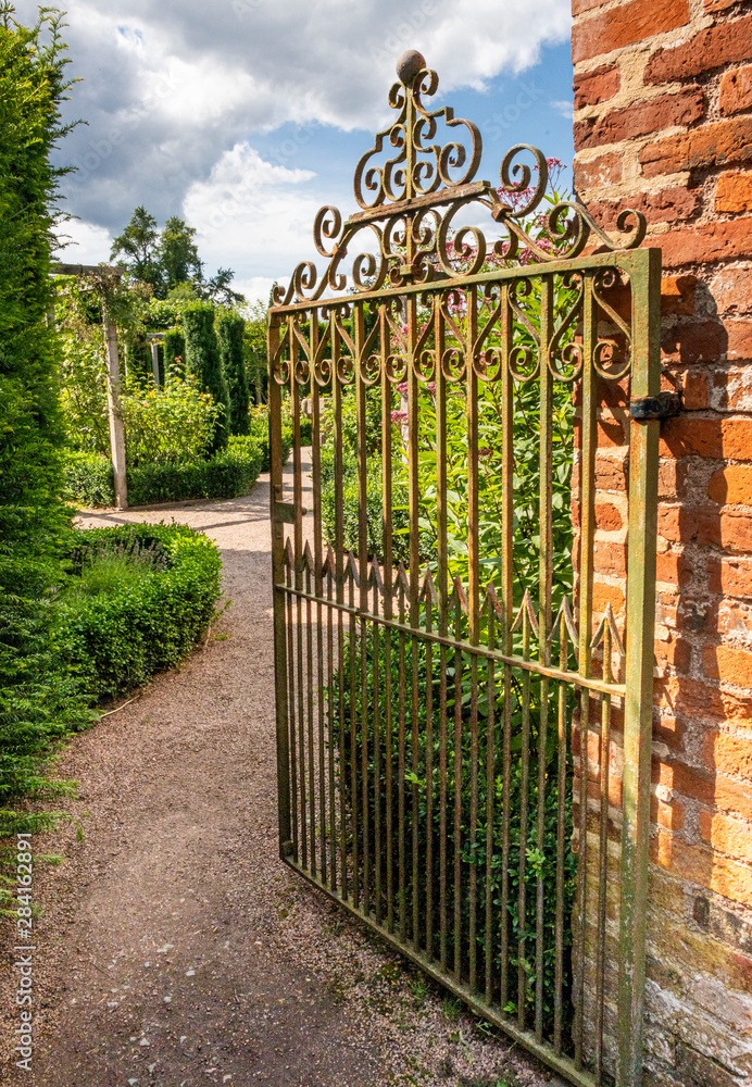 Rusty wrought iron gate opening into walled garden England Stock Photo ...