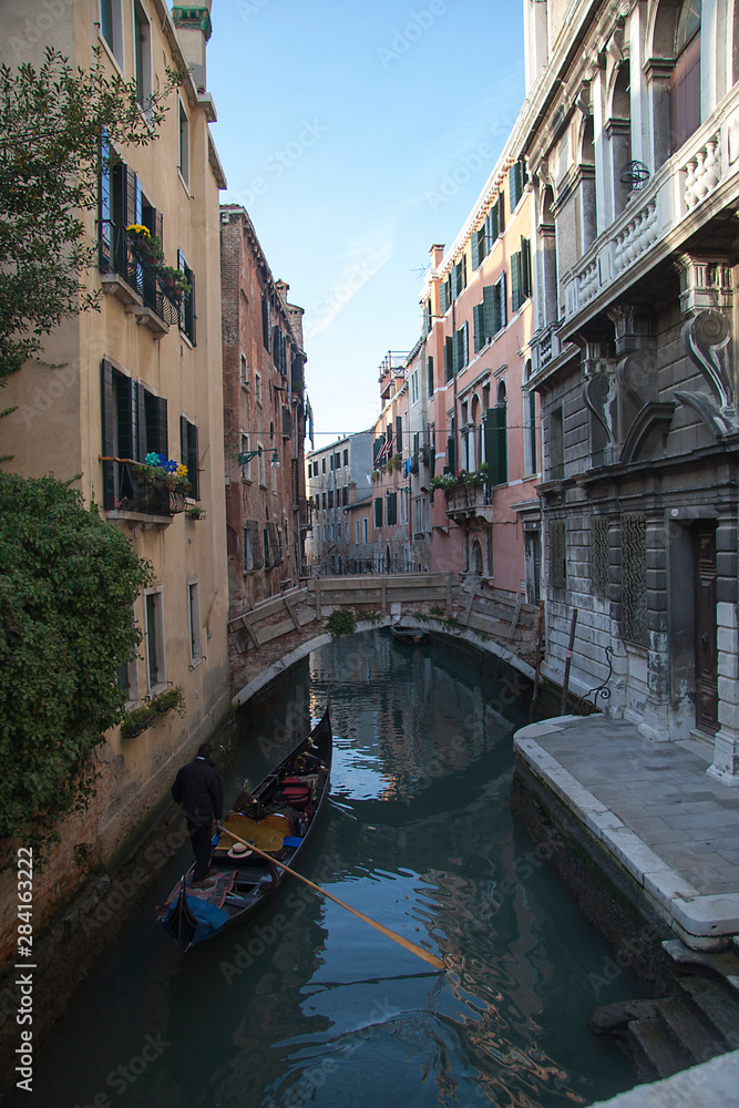 Venice winter mysterious romantic: Gondola sailing with parsimony between the canals, crossing under bridges