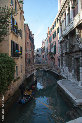 Venice winter mysterious romantic: Gondola sailing with parsimony between the canals, crossing under bridges