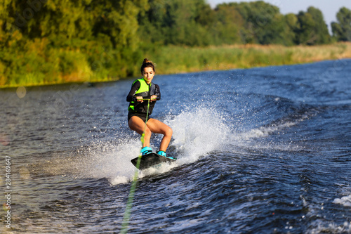 Young Sexy girl Catch waves on wakeboard when boat pulls a wakeboard 