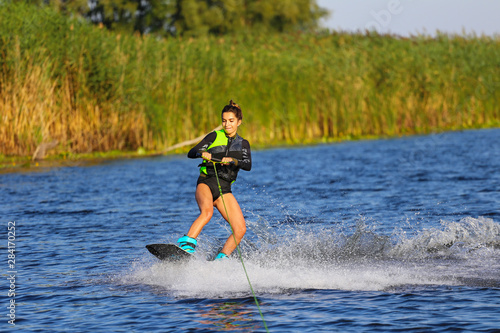 Young Sexy girl Catch waves on wakeboard when boat pulls a wakeboard 